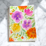 Hand-painted 5x7-inch greeting card featuring bold, layered watercolor florals in orange, yellow, pink, and purple on textured paper, with matching motifs on the envelope and inside.