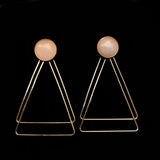 Image of rose quartz earrings with two, thin gold plated, overlapping triangles underneath, on a black background.