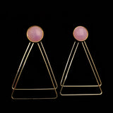Image of faceted pink earrings with two, thin gold plated, overlapping triangles underneath, on a black background.