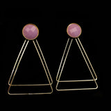 Image of faceted mauve earrings with two, thin gold plated, overlapping triangles underneath, on a black background.
