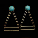 Image of turquoise earrings with two, thin gold plated, overlapping triangles underneath, on a black background.